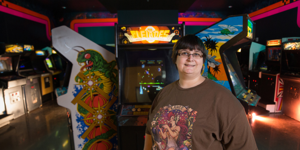 April Pruitt stands in front of a collection of video games.