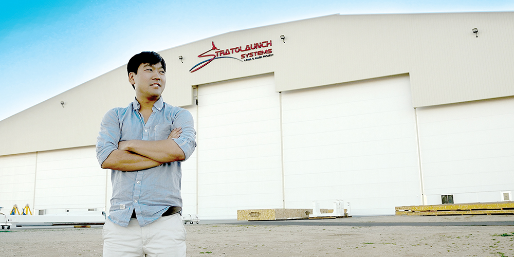Stuart Yun stands in front of a hangar