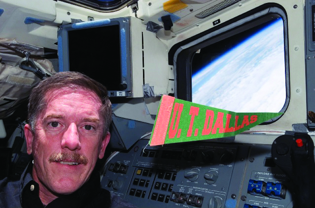 Astronaut and alumnus Dr. James Reilly holds a UTD flag.