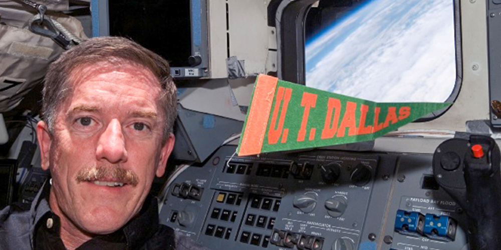 Reilly holds a UT Dallas banner in space