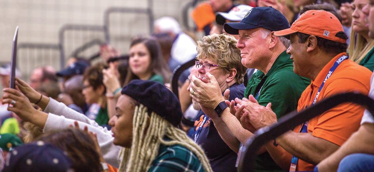 President Benson claps while sitting in the stands at a basketball game