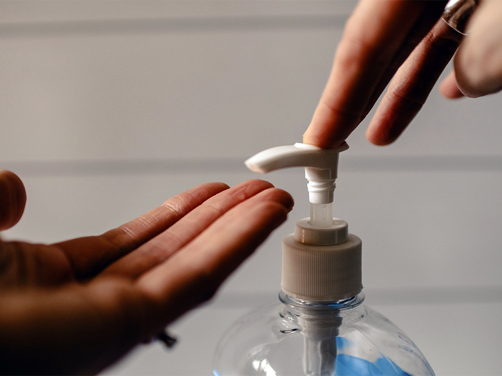 A person presses a hand sanitizer pump
