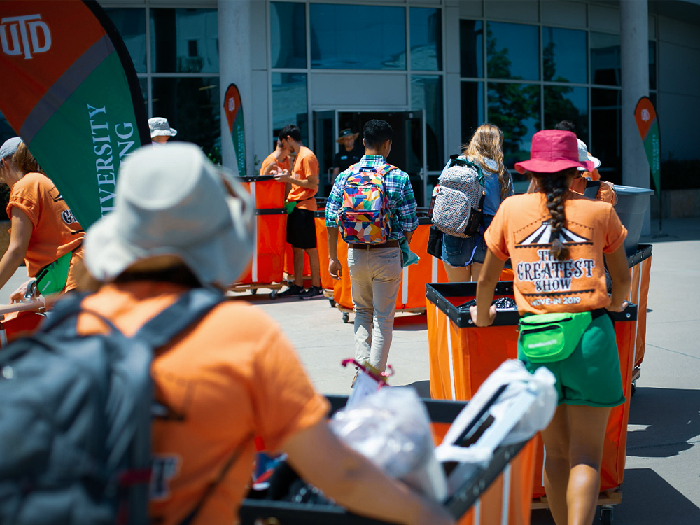 Line of volunteers with carts of student luggage