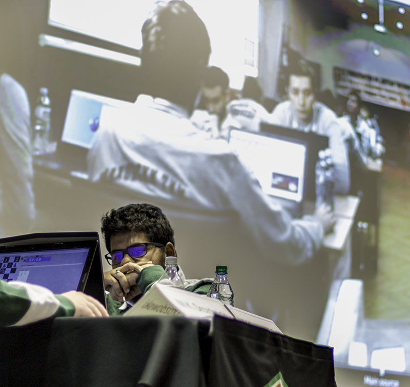 Prasanna Rao of the UT Dallas chess team plays his match as the University of Belgrade team is displayed on the projection screen.