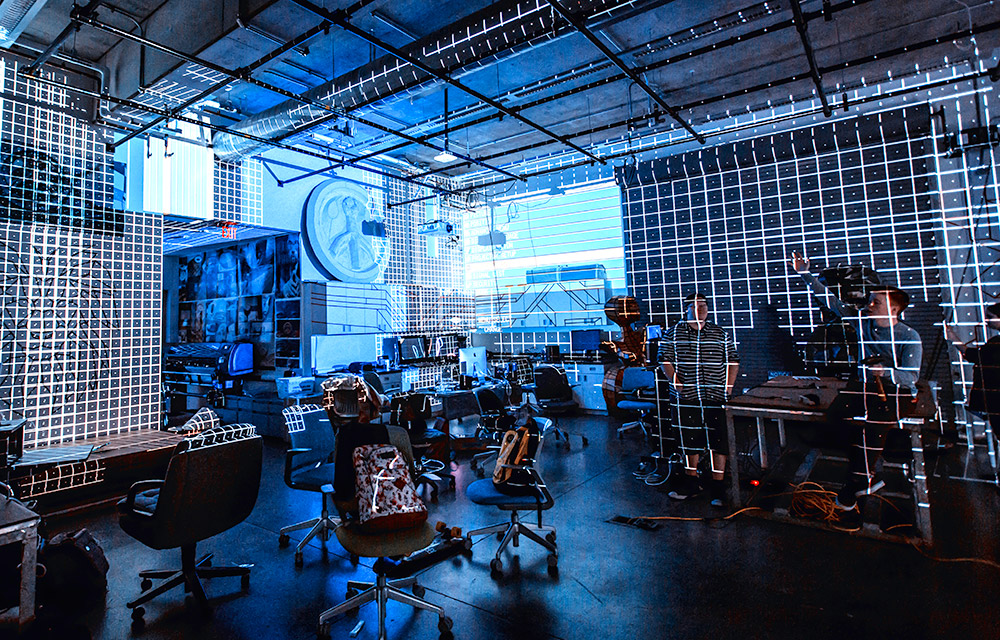 gridlines projected on the walls and ceiling of a blue-lit studio space