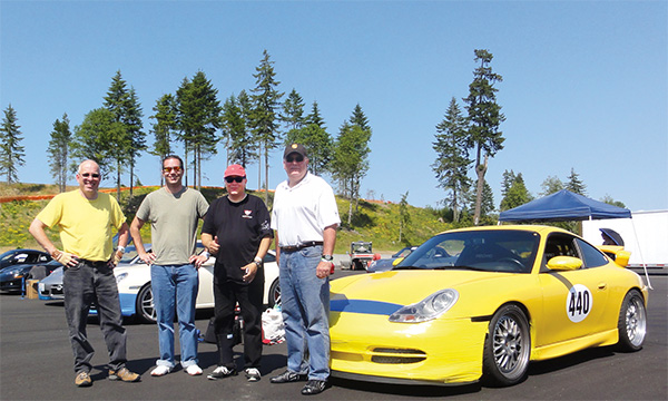 Belady (left) with his racing friends and his yellow Porsche.