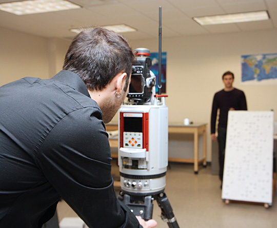 Graduate student Graham Mills, foreground, prepares terrestrial laser scanning equipment for a test run in a geosciences lab at UT Dallas while fellow grad student Dimitrios Bolkas adjusts the target object to be scanned.