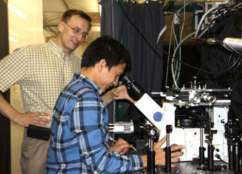 Dr. Anton Malko, a UT Dallas physics professor,  watches a grad student use a micrscope