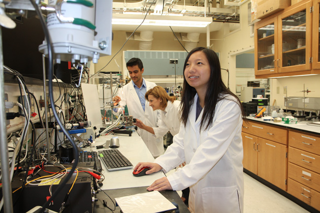 At UT Dallass NanoTech Institute, research associates Dr. Mrcio Dias Lima and Dr. Monica Jung de Andrade adjust an apparatus that tests the strength of a carbon nanotube yarn, while graduate student Na Li monitors the results.