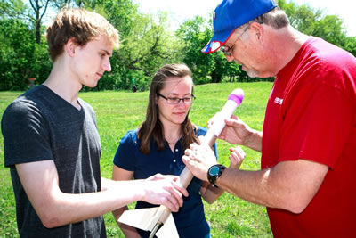 UT Dallas physics professor Phil Anderson (right) assists teammates Matthew Henderson, a physics junior, and Mikaela McMurtry, an interdisciplinary studies junior, to prepare their rocket for launch.