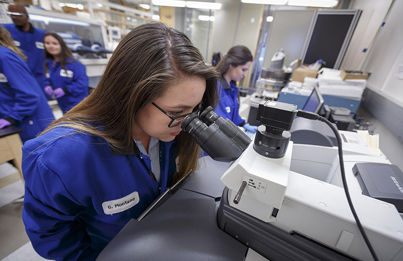 A student uses a research microscope during a materials science and engineering lab.
